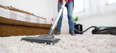 lady vacuuming carpet to clean it 1
